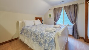 A bedroom with a bed, white curtains, a window, and a radiator.