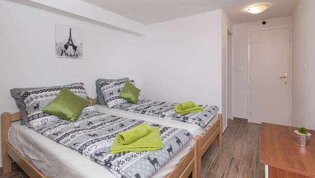 Habitación doble con dos camas, una mesa de madera y una puerta.