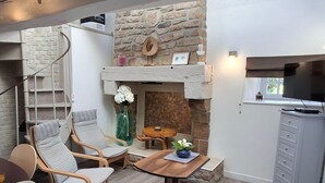 A cozy room with a stone fireplace, wooden furniture, and a television. - Cozy Stone Cottage with Private 8ha Fishing Pond and Scenic Surroundings - Ideal for Nature Lovers (Alexain)