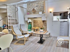 Una sala de estar acogedora con chimenea de piedra, asientos cómodos y un televisor.