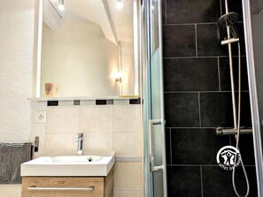 Un baño moderno con cabina de ducha de vidrio, un lavabo blanco y un espejo encima.