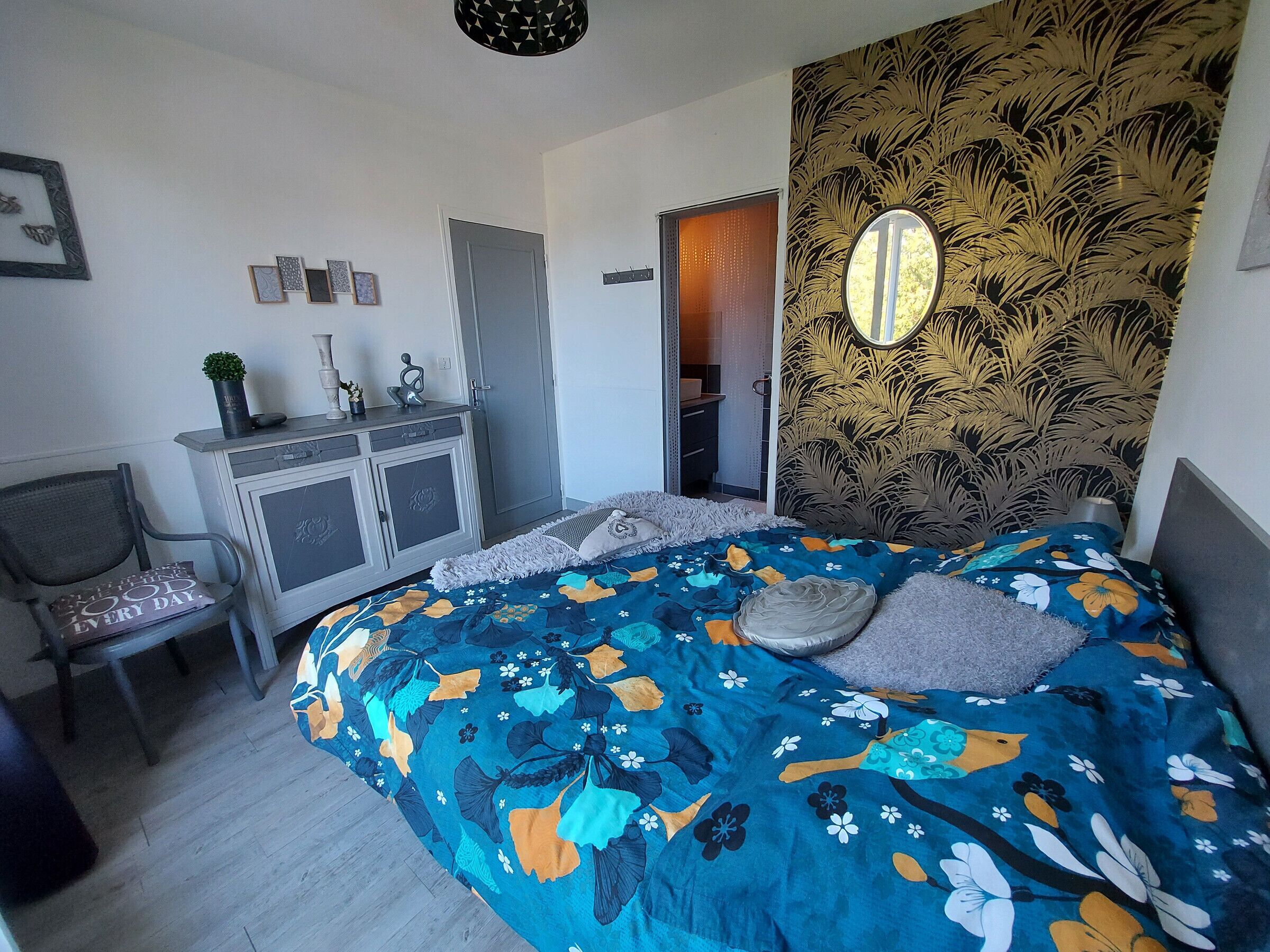 A bedroom with a bed, a desk, a chair, a wardrobe, and a mirror.