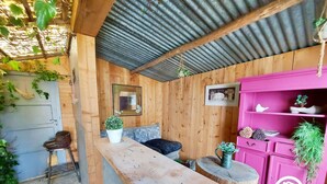 A rustic wooden room with a wooden bench, a small table, and a pink cabinet with plants. - Charming 4-Bed House with Garden, 10min from Laval, Ideal for Families and Professionals (Courbeveille)