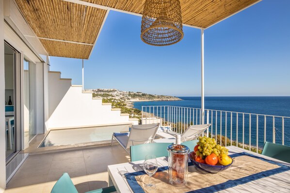 Une terrasse avec une table dressée pour deux personnes, offrant une vue sur la côte.