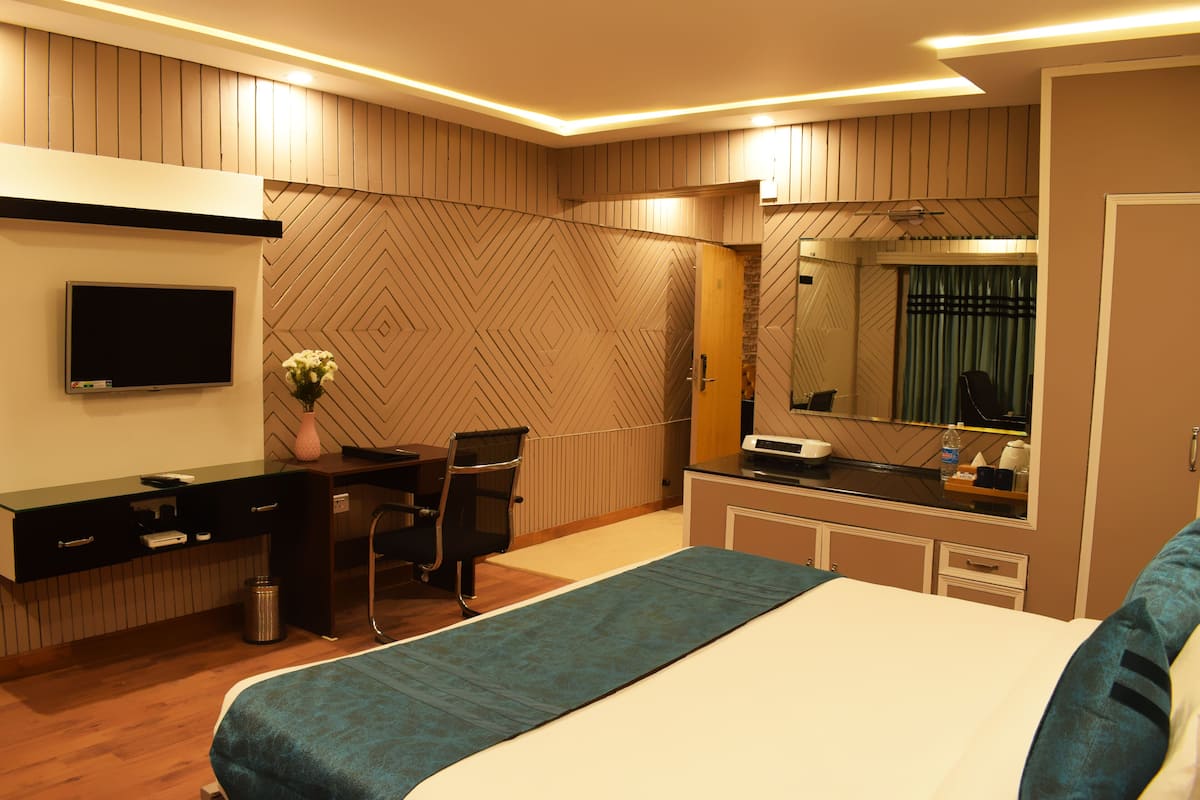 A modern hotel room with a bed, desk, chair, and a large mirror.