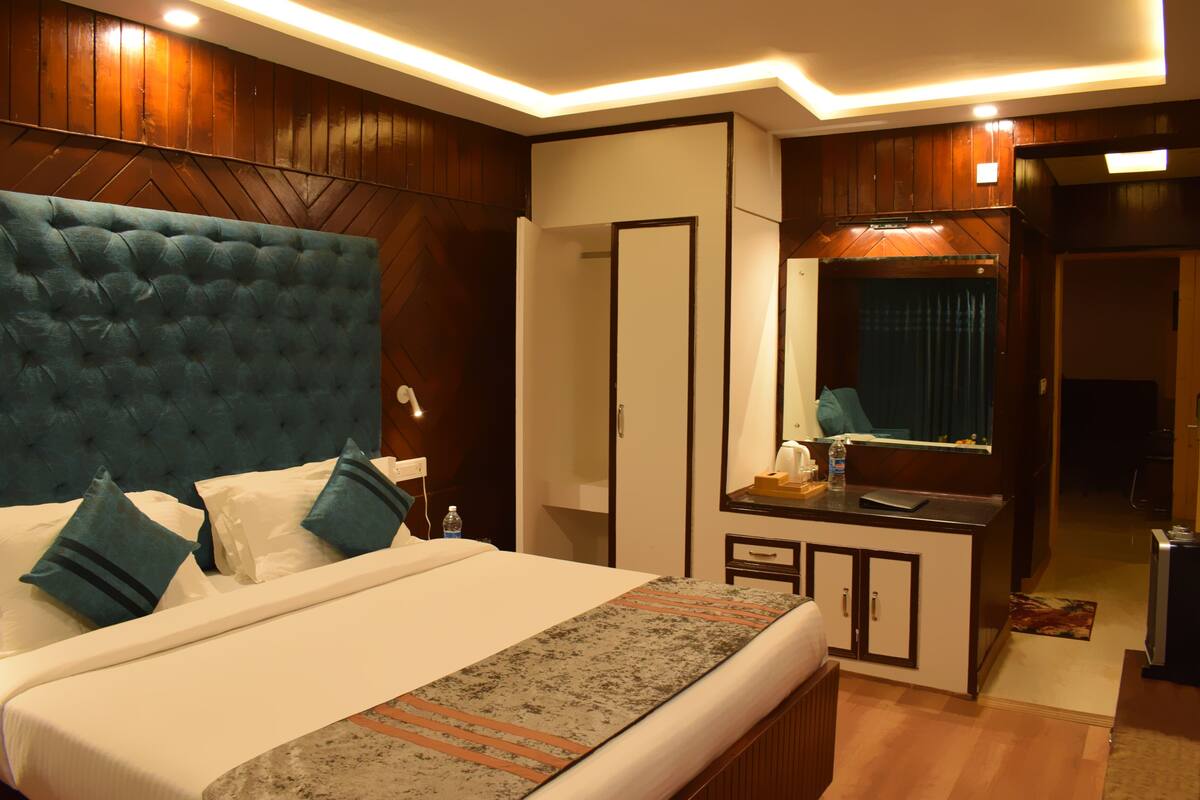 A hotel room with a large bed, a bedside table, a mirror, and a wardrobe.