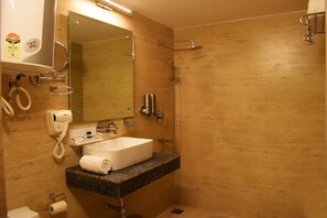 Un baño con pared de madera, un lavamanos con una toalla, un espejo, una ducha y un secador de pelo.