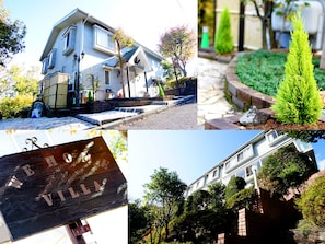 A two-story house with a front porch, a small garden, and a wooden sign with text. - We Home Villa Jyougasaki Onsen (Ito)