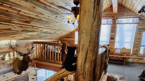 A wooden staircase with a bear head mounted on the wall, a deer head on the railing, and a chandelier. - 15 min to Yellowstone. Newly built in 2018 this cabin is meticulous . WIFI ÷ AC (Island Park)