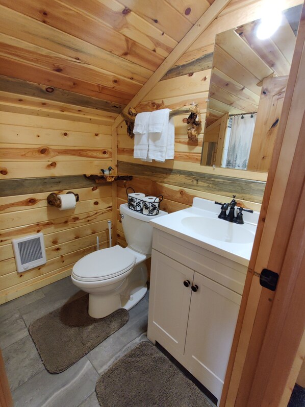 Un baño de cabaña de madera con inodoro, lavabo y espejo.