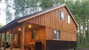 A wooden cabin with a porch, a covered seating area, and a small outdoor table. - 15 min to Yellowstone. Newly built in 2018 this cabin is meticulous . WIFI ÷ AC (Island Park)