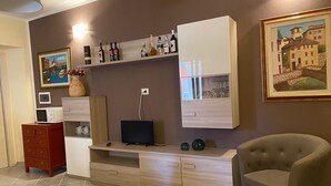 Un salon avec un téléviseur, un meuble de rangement en bois et un canapé.