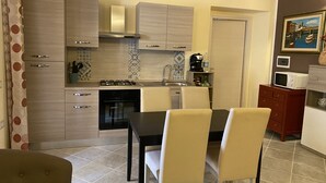 Une cuisine compacte avec un coin repas, comprenant une cuisinière, un four, un four à micro-ondes et un petit réfrigérateur.