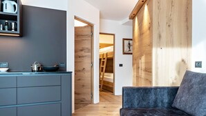 Eine moderne Küche mit grauen Schränken, einer Holzbank und einem grauen Sofa.