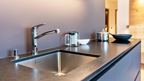Eine moderne Küche mit Spüle aus Edelstahl, einem Wasserkocher und einer Schüssel auf der Arbeitsplatte.