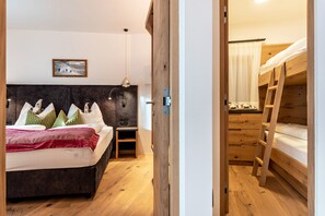 Un dormitorio con cama, mesita de noche, lámpara y una cama individual en la habitación contigua.