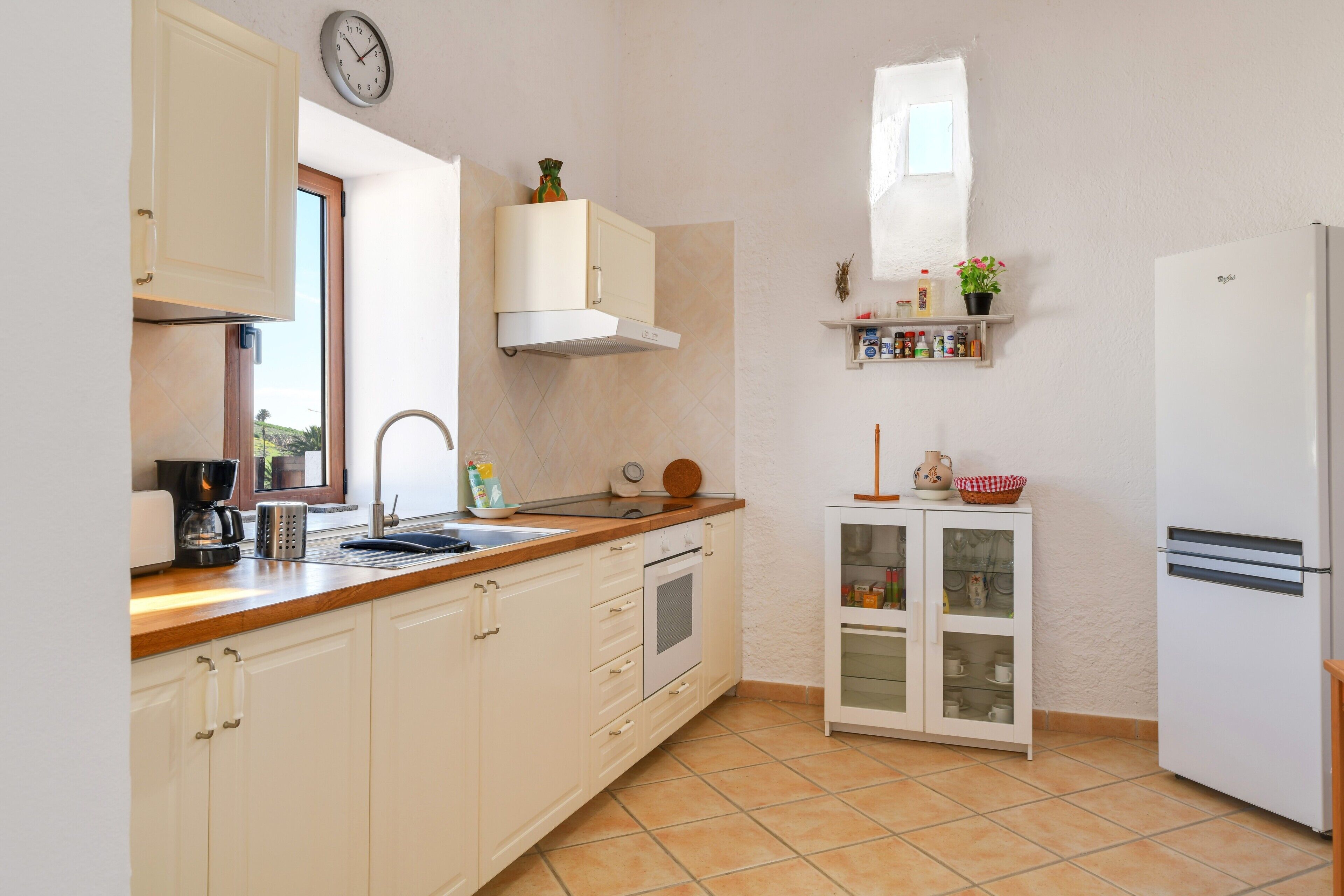 A kitchen with white cabinets, a built-in oven, a coffee maker, and a refrigerator.