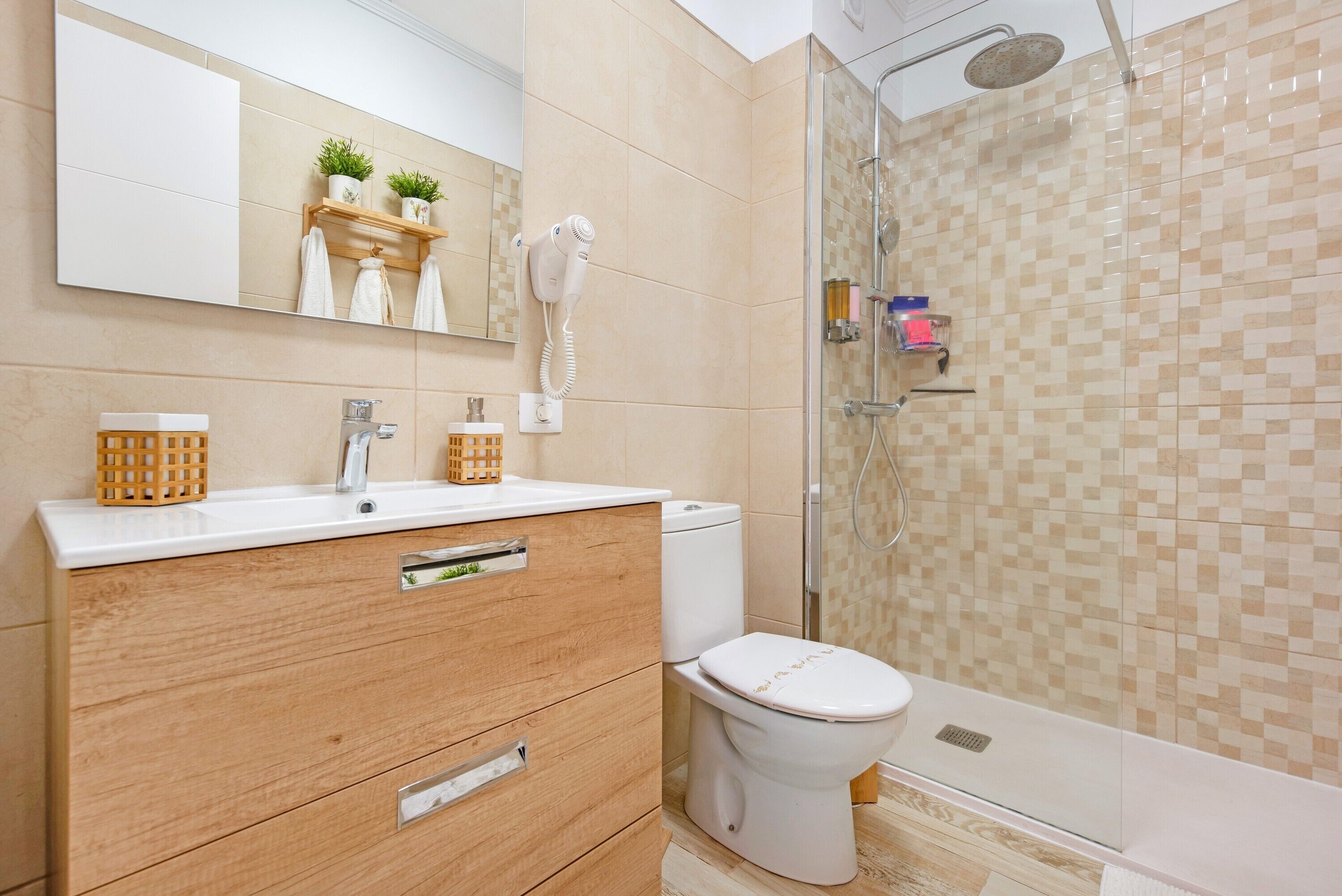 Een badkamer met toilet, wastafel, spiegel, haardroger en douche.