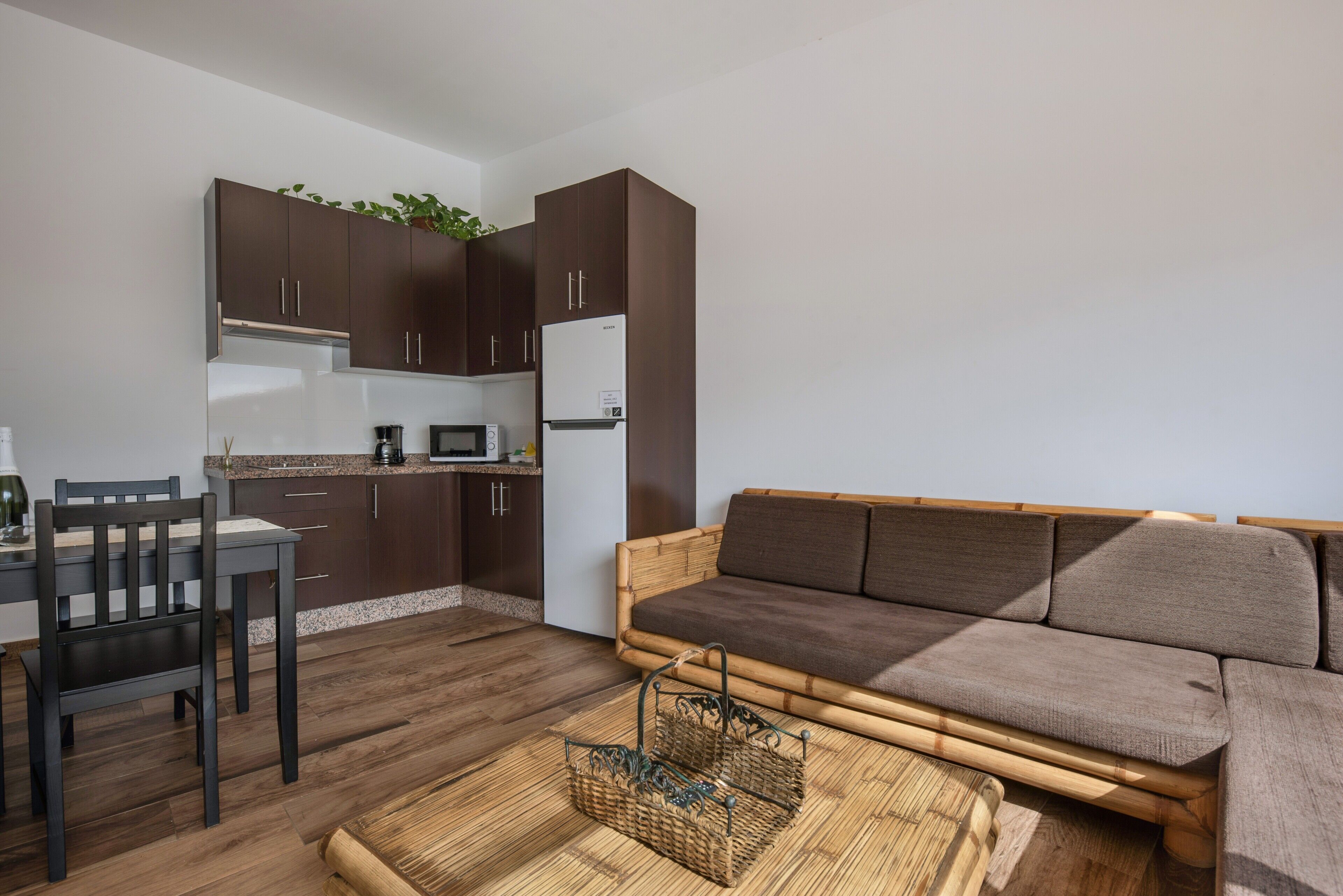 Um espaço compacto para viver com sofá, mesa de jantar, cadeiras e cozinha.