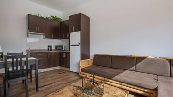 Um espaço compacto para viver com sofá, mesa de jantar, cadeiras e cozinha.