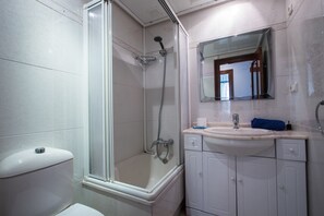 Bany amb dutxa tancada amb vidre, vàter, rentapla i armaris.