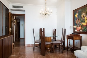A dining area with a round glass table, four chairs, a chandelier, and a painting on the wall. - VERALUX 2. (BENIDORM)