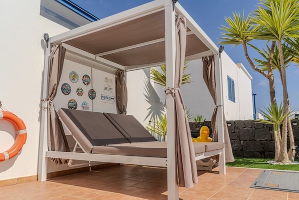 A sunbed with a canopy, a lifebuoy, and a wall with various stickers.