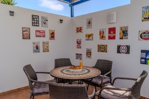 A patio with wicker chairs and a round table, surrounded by various beer and wine posters.