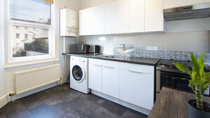 Een moderne keuken met witte kasten, een ingebouwde wasmachine, een kookplaat en een spoelbak.
