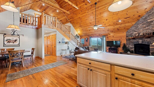 A spacious living area with a wooden ceiling, a fireplace, a dining area with a table and chairs, and a staircase leading to an upper level. - Serenity Hill 42 Midland Drive: 3  BR, 3  BA Cabin / Bungalow in Waynesville, Sleeps 6 (Waynesville)
