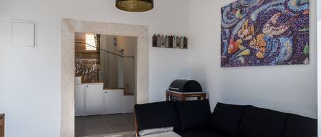 A modern living room with a black sofa, a wooden coffee table, and a large abstract painting on the wall.