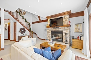 A spacious living room with a fireplace, a staircase, and a cozy seating area. - Le Plateau Ski In/Out w/ 3bdrs w/ Pool Access (Mont-Tremblant)