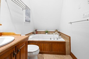 Ein Badezimmer mit einem Holzbadezimmer-Möbel, einem weißen Waschbecken, einer Toilette und einer freistehenden Badewanne.