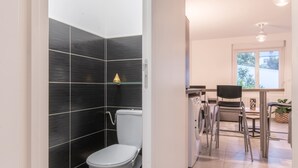 A modern bathroom with a toilet, a washing machine, and a chair.