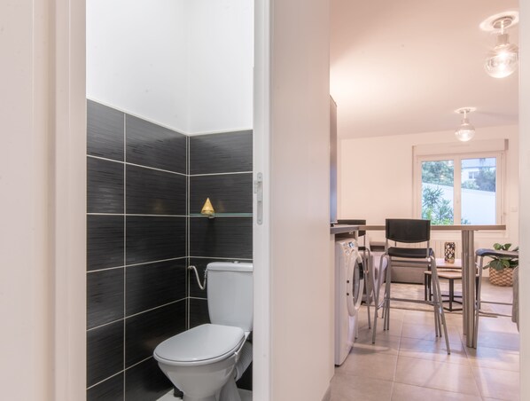 Une salle de bain moderne équipée de toilettes, d’un lave-linge et d’une chaise.