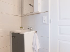 Une salle de bain moderne avec un lavabo blanc, un meuble sombre et une serviette accrochée au mur.