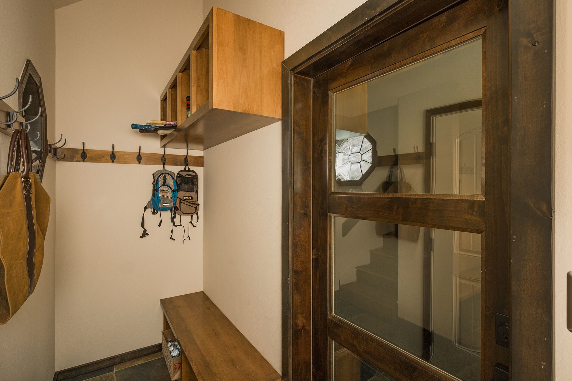 Un corridoio con una panca di legno, un appendiabiti e uno scaffale con borse.
