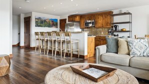 A modern kitchen with wooden cabinets, stainless steel appliances, and a bar area with bar stools. - Penthouse in Purgatory Lodge - Views - Ski in/Out - Pool Table (Durango)