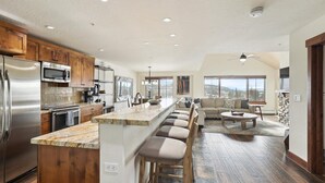A spacious kitchen with a central island, wooden cabinets, and a large window overlooking a scenic view. - Penthouse in Purgatory Lodge - Views - Ski in/Out - Pool Table (Durango)