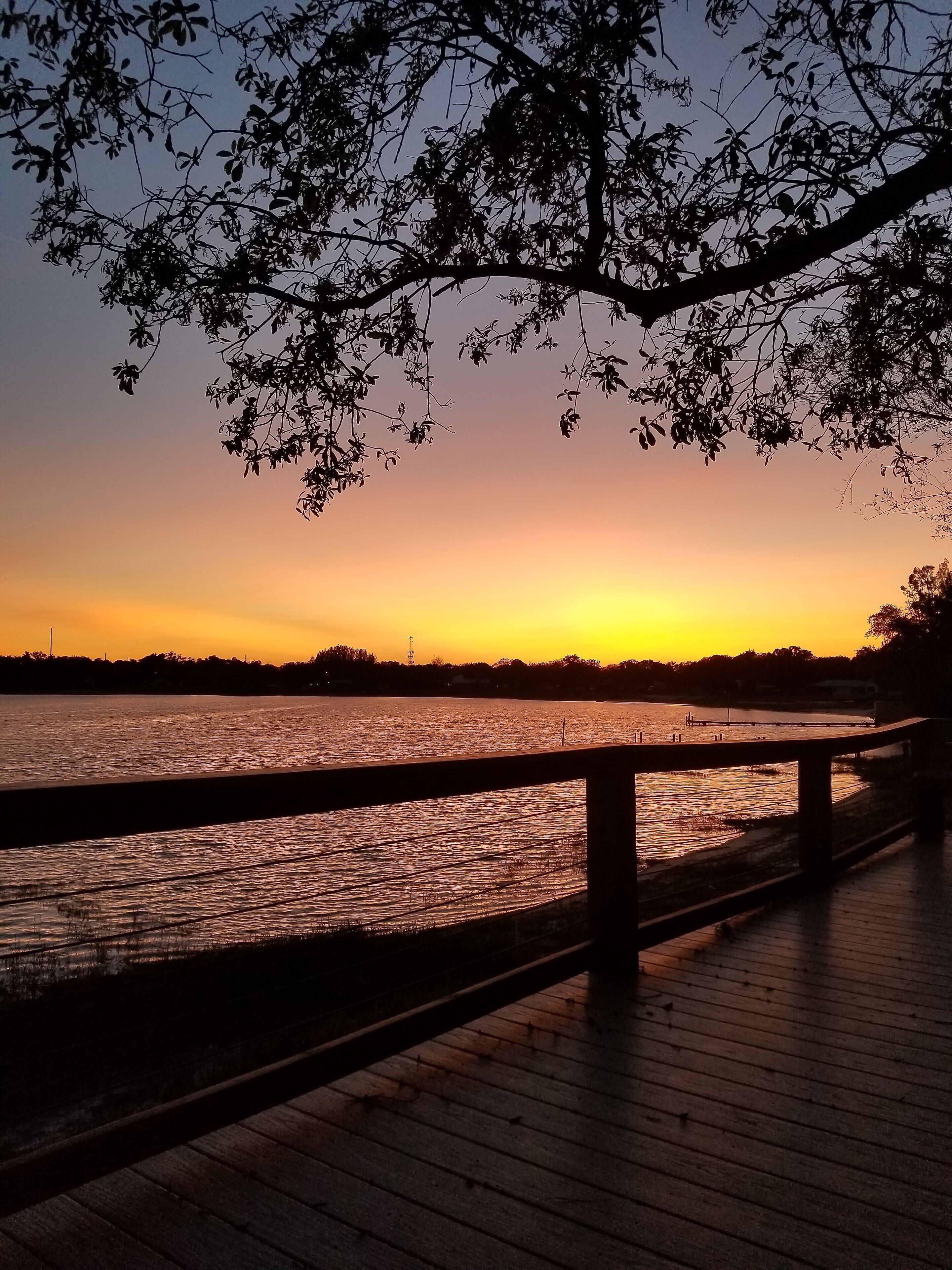 A wooden deck overlooking a body of water during sunset.