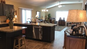 A spacious kitchen with a central island, built-in appliances, and a dining area with a sofa and lamp.