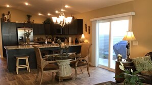 A spacious kitchen with dark cabinets, a central island, and a dining area with a chandelier.