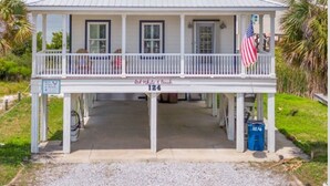 A two-story house with a balcony, a porch, and an American flag.