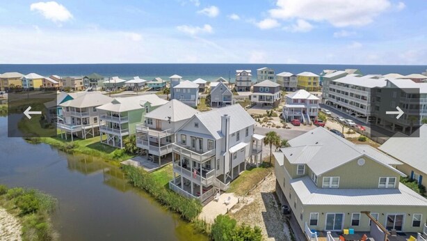 A coastal residential area with multi-story houses, a marina, and a clear view of the ocean.