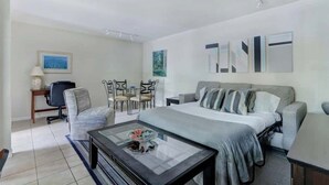 Una habitación de hotel moderna con una cama, una mesa de centro de vidrio, un escritorio y una silla.