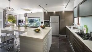 Una cocina moderna con una isla grande, electrodomésticos de acero inoxidable y vistas al exterior.