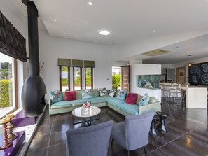 A modern living room with a sectional sofa, a round coffee table, and a large black stove. - Protaras Oscar Domain Villa A4 (Protaras)