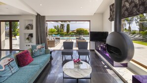 Una sala de estar moderna con sofá, sillones, televisor y chimenea.