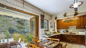 Una cocina con armarios de madera, una mesa de comedor con sillas y vistas a un paisaje montañoso.