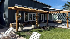 A modern house with a covered patio, outdoor seating, and potted plants.
